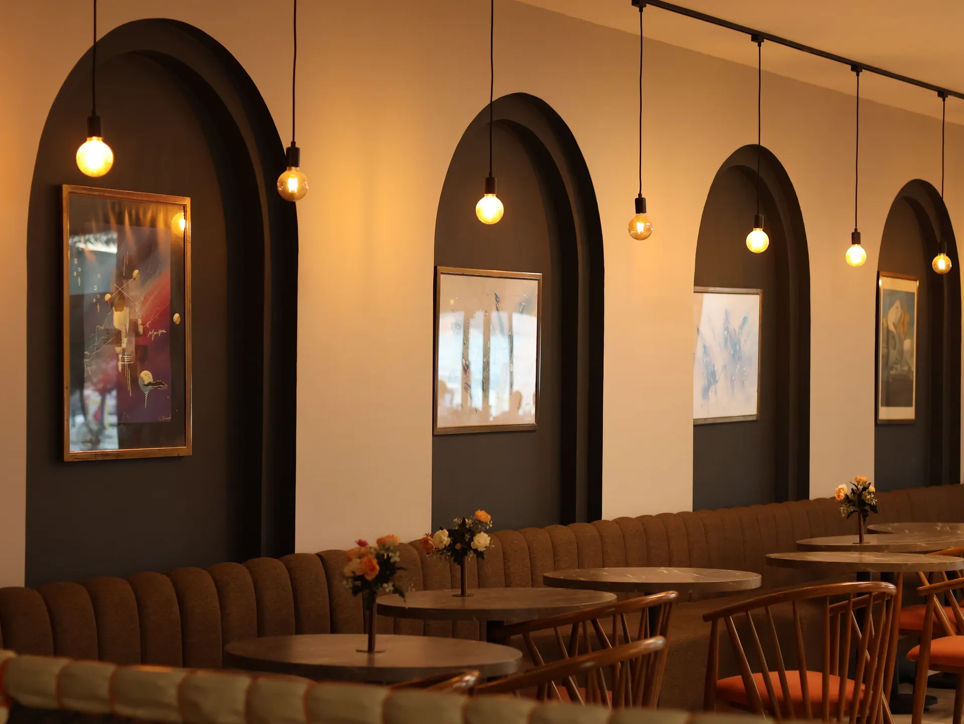 Café interior with arched wall recesses, pendant lights and banquette seating