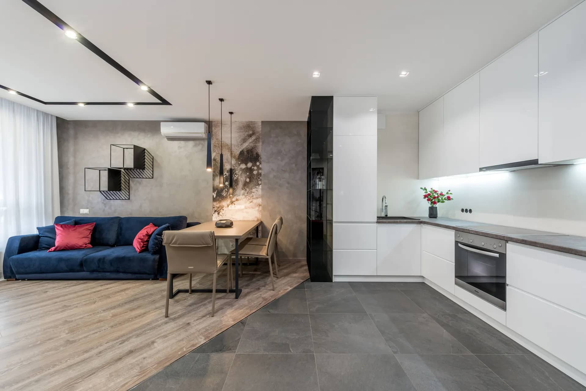 Open-plan apartment with a sofa area, dining table and a fitted kitchen along one wall
