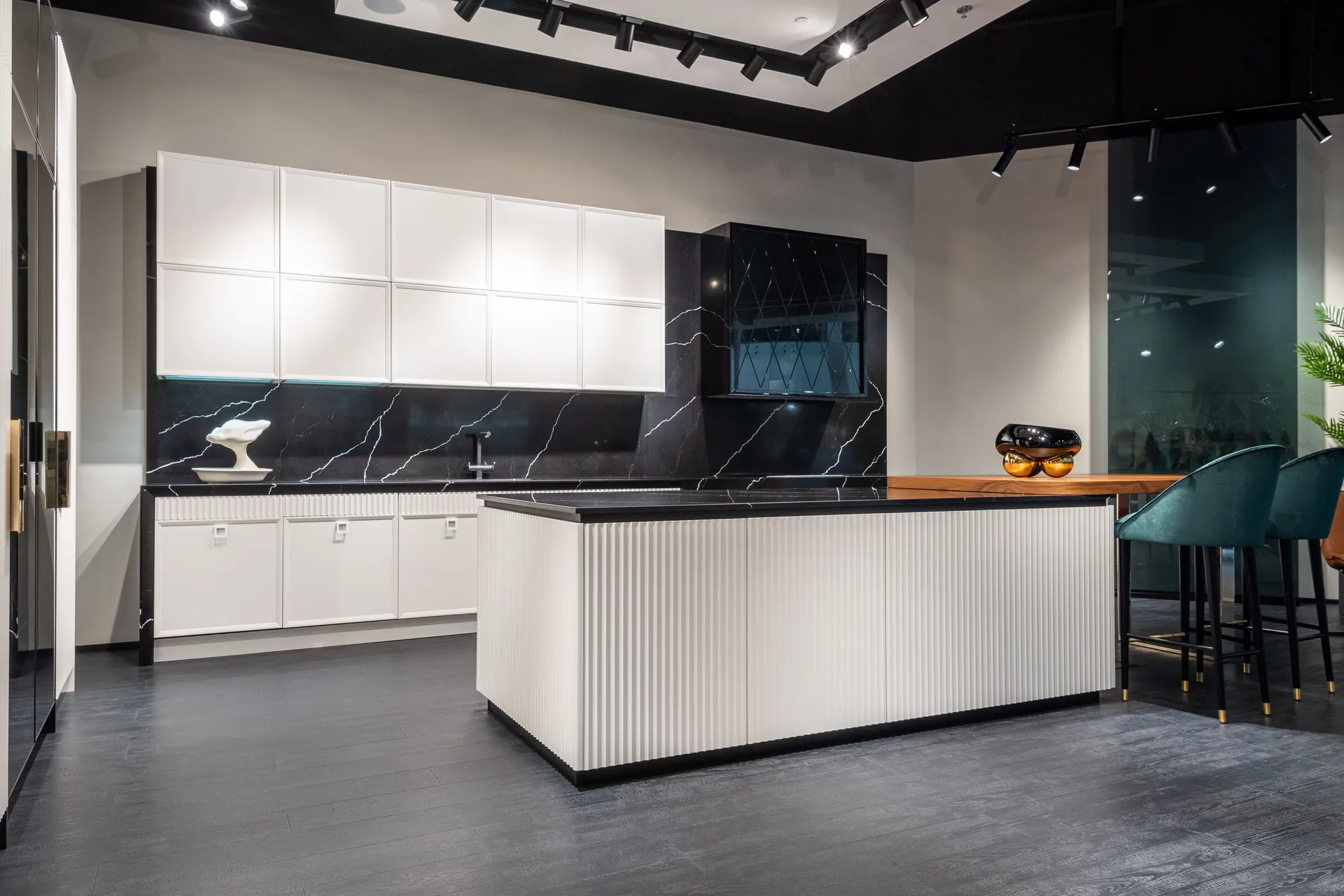 Kitchen with a fluted island, white cabinetry and a dark stone splashback